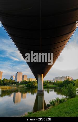 Perspektivische Ansicht der U-Bahn-Brücke Hůrka–Lužiny über einen Teich in einem Park in Prag, Tschechien Stockfoto