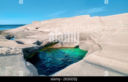 Einzigartige weiße Felsen und smaragdgrünes Wasser in Meereshöhle, Sarakiniko Strand, Insel Milos, Griechenland. Leere Klippen, Sommersonne, klarer blauer Himmel Stockfoto