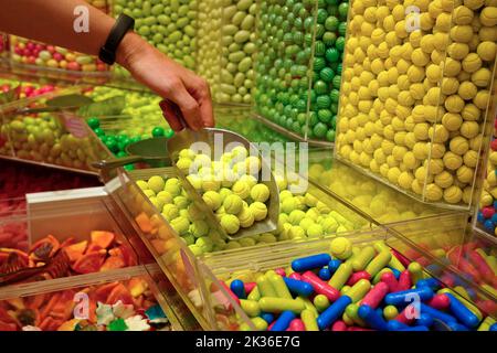 Frau Hand mit Schaufel, die bunte leckere Süßigkeiten auf der Theke von Geschäft, Lebensmittelgeschäft, Markt, Café. Stockfoto