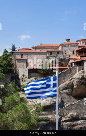 Schwenkende griechische Flagge vor dem Großen Meteoron Kloster. Meteora, Griechenland (vertikales Foto) Stockfoto