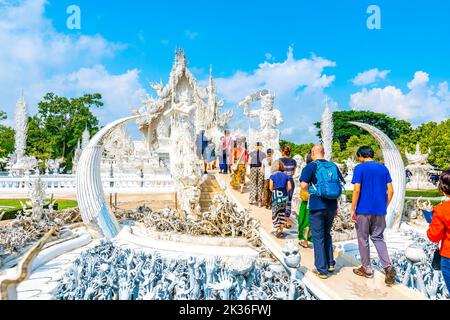 CHIANG RAI, THAILAND - 6.11.2019: Touristen besuchen den berühmten weißen Tempel (Wat Rong Khun) in der Nähe der Stadt Chiang Rai. Weißer Tempel mit Brücke über verdammte Seelen Stockfoto