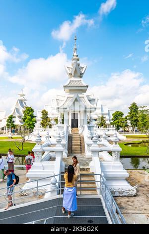 CHIANG RAI, THAILAND - 6.11.2019: Touristen besuchen den berühmten weißen Tempel (Wat Rong Khun) in der Nähe der Stadt Chiang Rai. Weißer Tempel mit Brücke über verdammte Seelen Stockfoto