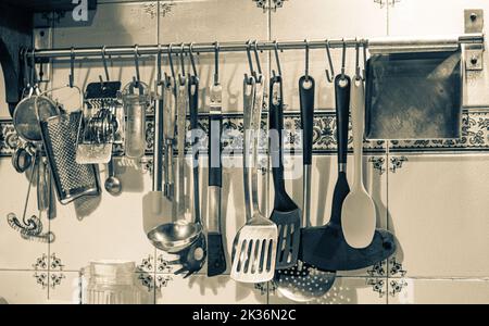 Schwarzweiß-Foto. Küchenutensilien hängen an der Wand. Stockfoto