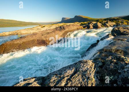 Goldene Stunde bei den Stromschnellen des Stuor Muorkke Wasserfalls im Stora Sjofallet Nationalpark, Schweden. Abenteuer in arktischer Wildnis. Schöner sonniger Tag in Stockfoto