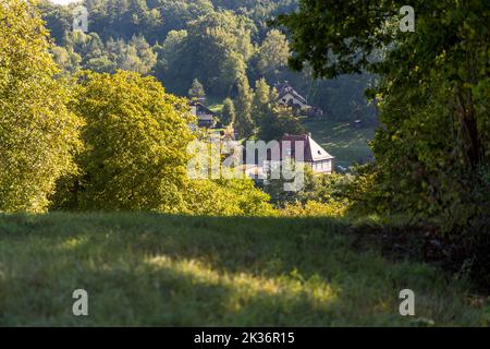 Ein Fachwerkhaus mit einem roten Ziegeldach steht versteckt zwischen Bäumen im Wald nahe Lichtenfels, Bayern, Deutschland. Das Gebäude liegt am Wacholderweg, nicht weit von einem in den Sandstein gehauenen Felsenkeller entfernt. Stockfoto