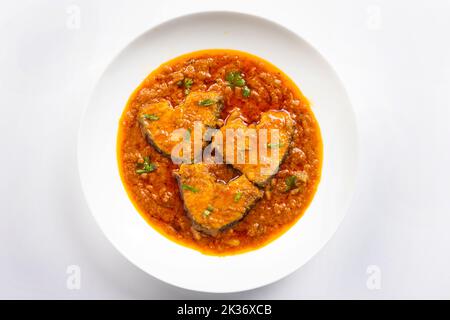 Katla Fish-Kerrys, traditionelles indisches Fischurrys, arrangiert in einer weißen Keramikschale, garniert mit frischen roten Chilli. Isoliert auf weißem Hintergrund, oben Stockfoto