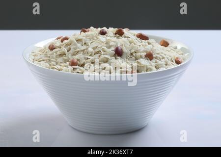 Roher, abgeflachtes Reis oder dicke oder dünne Reisflocken für Namkeen Chivda Snacks oder Aloo Poha für indisches Frühstück, serviert in einer Schüssel. Stockfoto