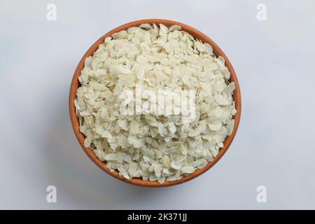 Roher, abgeflachtes Reis oder dicke oder dünne Reisflocken für Namkeen Chivda Snacks oder Aloo Poha für indisches Frühstück, serviert in einer Schüssel. Stockfoto