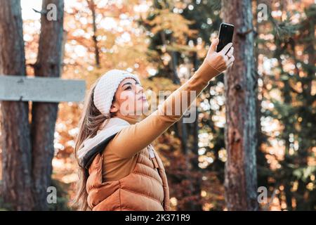 Junge, brünett weibliche Person fangen Telefonsignal im Wald Stockfoto