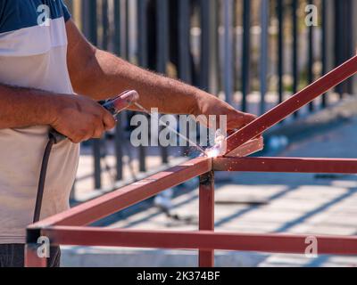 Schweißer schweißen an einem sonnigen Tag zwei Eisenprofile auf der Baustelle Stockfoto