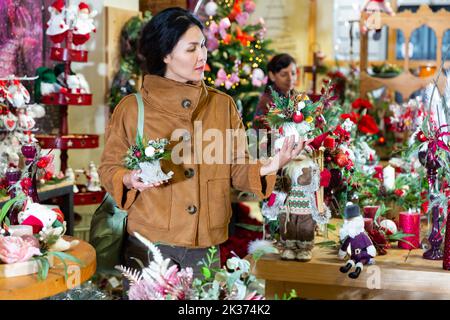 Positive asiatische Frau wählt eine Weihnachtskomposition Stockfoto