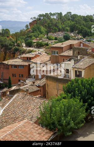 Das hochgelegene Dorf Roussillon (Südfrankreich) mit dem Beginn des Ocher Trails im Hintergrund. Stockfoto