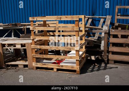 Ein Stapel Holzkisten und Paletten gegen die blaue Wand Stockfoto