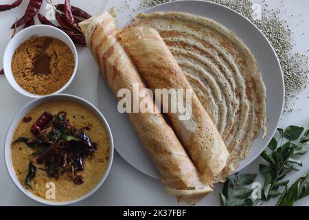 Bajra Ghee Braten. Dünne knusprige Crepes mit einem fermentierten Teig aus Perlenhirse und Linsen, die Ghee hinzufügen. Serviert mit würzigen Kokosnusswürzen. Aufnahme Stockfoto