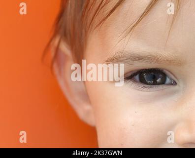 Teil des Gesichts des Kindes. Orangefarbener Hintergrund Stockfoto