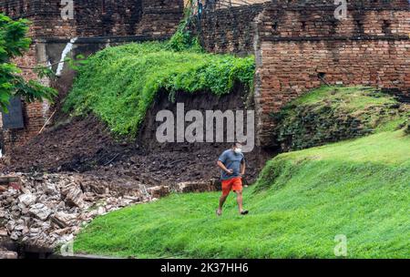 Chiang Mai, Thailand. 25. September 2022. Ein Mann sah, wie er am Chang Phuak-Tor im Bezirk Muang in Chiang Mai vorbei an der Mauer ging, die durch starken Regen zusammenbrach. Die alte Stadtmauer von Chiang Mai, in der Nähe des Chang Phuak-Tores, stürzte gestern Abend aufgrund des starken Regens teilweise ein, was Beamte des Fine Arts Department und der Gemeinde Chiang Mai dazu veranlasste, den Schaden vor Beginn der Renovierungsarbeiten zu beurteilen. Kredit: SOPA Images Limited/Alamy Live Nachrichten Stockfoto