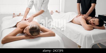 Wunderschönes Paar, das im Spa-Salon eine Rückenmassage bekommt. Hübscher Mann und hübsche Frau entspannen sich bei einer Rückenmassage Stockfoto
