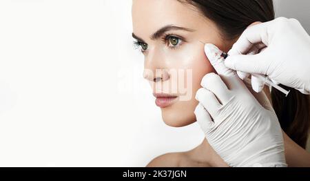 Schöne Frau während der Gesichtsmesotherapie zur Glättung von Mimikfältchen um die Augen mit Kosmetikerin. Schönheitsinjektionen zur Verjüngung und Liftski Stockfoto