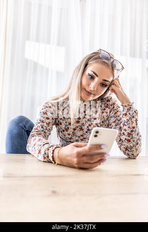 Eine junge Frau nutzt ein Smartphone, schreibt eine SMS oder durchsucht soziale Netzwerke. Stockfoto