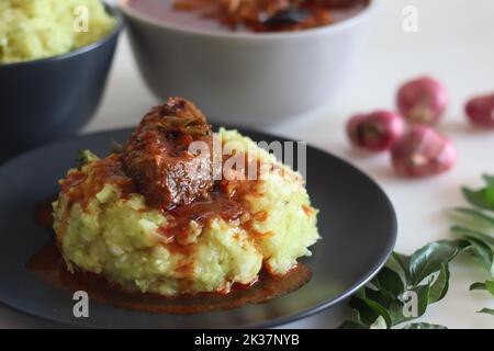 Pürierte Tapioka serviert mit Pomfret-Fisch-Kerrbejau. Gekochte und strainierte Tapiokastücke, die mit gewürzter Kokosnuss püriert sind, schmecken am besten mit Fischurrfleisch Stockfoto