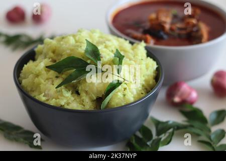 Pürierte Tapioka serviert mit Pomfret-Fisch-Kerrbejau. Gekochte und strainierte Tapiokastücke, die mit gewürzter Kokosnuss püriert sind, schmecken am besten mit Fischurrfleisch Stockfoto