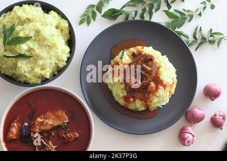 Pürierte Tapioka serviert mit Pomfret-Fisch-Kerrbejau. Gekochte und strainierte Tapiokastücke, die mit gewürzter Kokosnuss püriert sind, schmecken am besten mit Fischurrfleisch Stockfoto