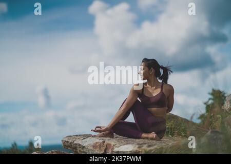 Eine junge Indianerin in Sportbekleidung, die Yoga auf einem Berg macht Stockfoto