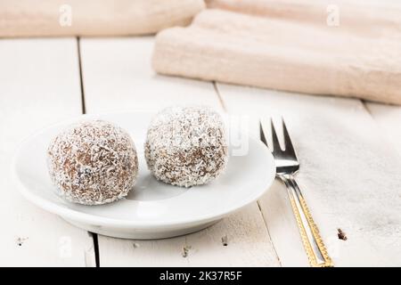 Kokoskuchen, Name Kokoskugel. Gefüllt mit gemischter Füllung. Traditionelles Weihnachtsdessert, ideal für die langfristige Lagerung. Serviert auf einem weißen Retro-Tisch. Stockfoto