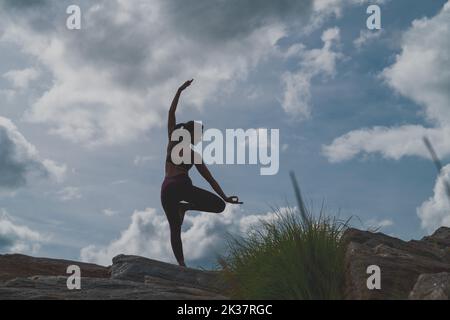 Eine junge Indianerin in Sportbekleidung, die Yoga macht, posiert auf einem Berg Stockfoto