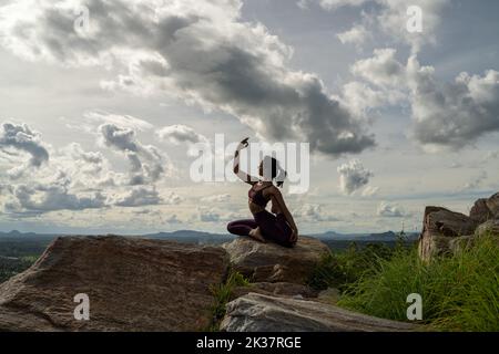 Eine junge Indianerin in Sportbekleidung, die Yoga macht, posiert auf einem Berg Stockfoto