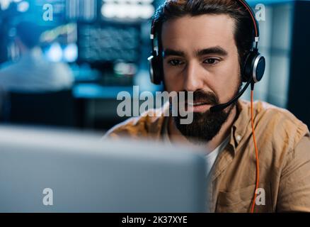 Junger Börsenhändler, der im dunklen Büro arbeitet Stockfoto