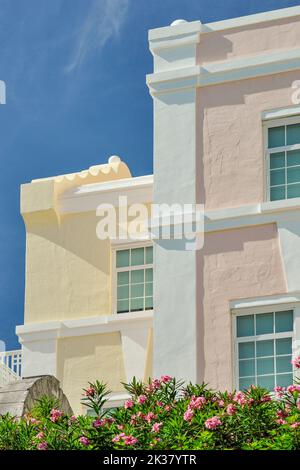 Hamilton Bermuda Architecture Close Up Pastell Pink & Yellow Gebäude vor tiefblauem Himmel mit weißen, wispigen Wolken Stockfoto