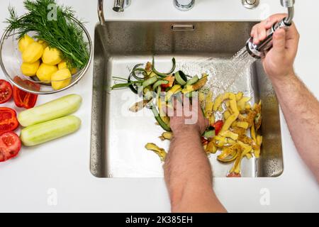 Modernes Waschbecken mit Lebensmittelabfällen im Loch des Entsorgungsers Stockfoto