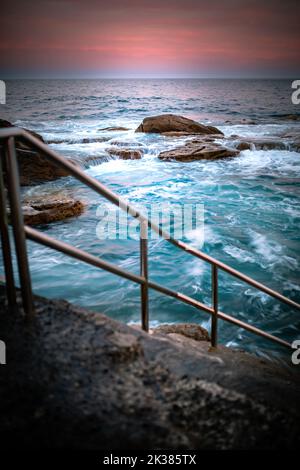 Swimmingpool am Meer in den warmen Tönen des Sonnenaufgangs in Sydney, New South Wales, Australien Stockfoto