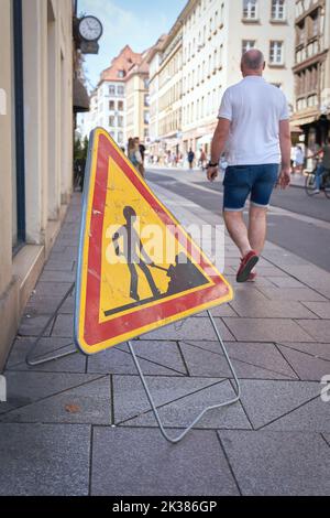 Baustellenschild und Passanten auf einem Bürgersteig in der Innenstadt von Straßburg, Frankreich Stockfoto