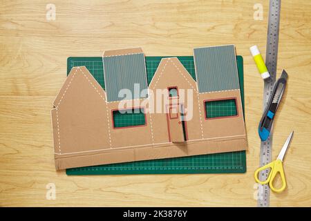 Ein buntes Bastelmuster aus Pappe, das geschnitten, fertig geformt und in ein Miniaturhaus geklebt wurde Stockfoto