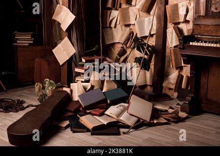 Bücher liegen auf dem Boden und hängen an den Wänden in einem dunklen Raum. Retro Stockfoto