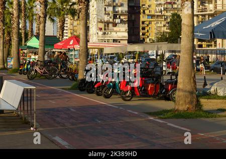 BATUMI, GEORGIA, AJARIA - 30. AUGUST 2022: Elektroroller, Fahrräder und andere Transportmittel auf dem Boulevard zu mieten. Stockfoto