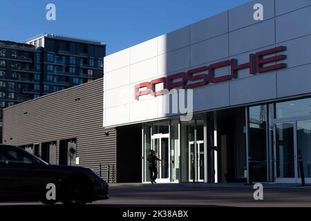 Die Fassade eines Porsche-Händlers wird am frühen Morgen gesehen, wenn ein Mann hereinkommt; Porsche ist ein deutscher Hochleistungs- und Luxusautos-Hersteller. Stockfoto