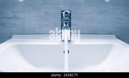 Wassermischer im Bad. Wasserhahn aus Chrom-Material, Wasserhahn mit Wasser in Blauton Stockfoto