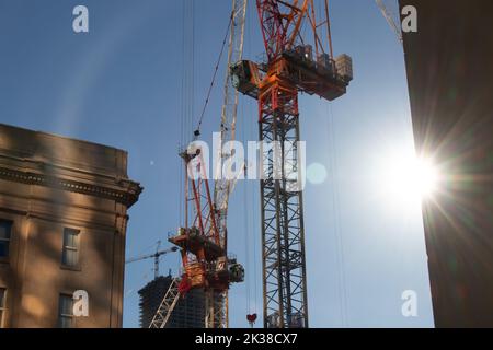 An klaren Tagen scheint die Sonne auf große Baukräne, die Bürogebäude in der Innenstadt von Toronto bauen. Stockfoto
