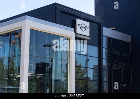 Die Vorderseite eines Mini-Autohauses ist an einem sonnigen Tag zu sehen, mit dem Mini-Logo auf dem Gebäude. Stockfoto