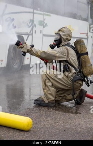 Ein Feuerwehrmann in einem Anzug mit Sauerstoffmaske löscht das Feuer. Stockfoto