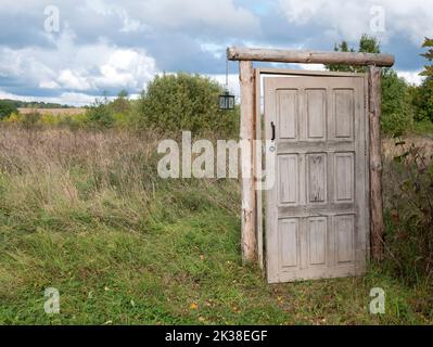 Entriegelte Tür, die ins nichts führt, Kopierraum. Altes Mystery-Portal im offenen Feld, selektiver Fokus Stockfoto