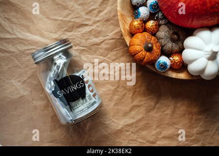 Sparen Sie Geld Halloween, Ersparnisse, Halloween auf Budget. Glas Einmachglas Sparschwein mit Dollar Bargeld auf Halloween Kürbis Dekoration Hintergrund Stockfoto