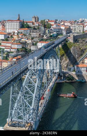 Porto, Portugal - 23. September 2022: Ein Zug, der an der Dom Luis I Brücke über den douro vorbeifährt. Porto alte Mauer und Skyline im Hintergrund. Stockfoto