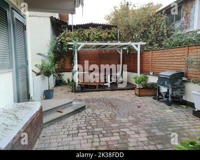 Pavillon mit Lichtern in der Nacht. Bild von einem Sommerhaus mit komfortablen Gartenmöbeln. Romantische Szene in der Dämmerung Stockfoto