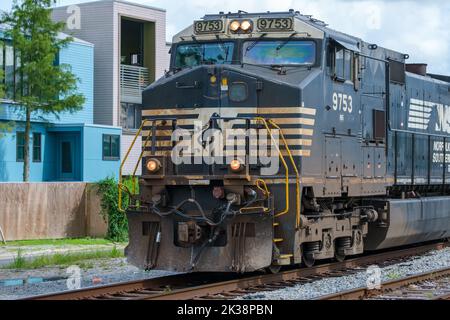 NEW ORLEANS, LA, USA - 12. AUGUST 2022: Norfolk Southern Lokomotive fährt nach Westen mit Wohngebäude im Hintergrund in Uptown New Orleans Stockfoto