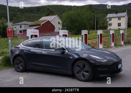 Skibotn, Norwegen - 25. Juli 2022: Eine statische Aufnahme eines soliden schwarzen Tesla Model 3 Dual Motor, der an einem bewölkten Sommertag am Skibotn Supercharger aufgeladen wird. Stockfoto