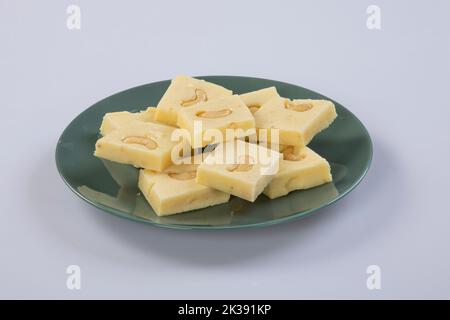 Kaju Katli ist eine traditionelle indische Diamant-förmige Süßigkeit oder Mithai, hergestellt aus Cashewpaste, Zucker und mava oder Khoya. Serviert auf einem Teller über Weiß. Stockfoto